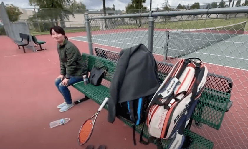 Mom sitting and watching us play tennis